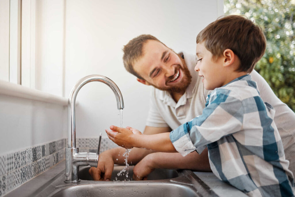 A dad and son washing hands at a sink after it received an NYC drain cleaning